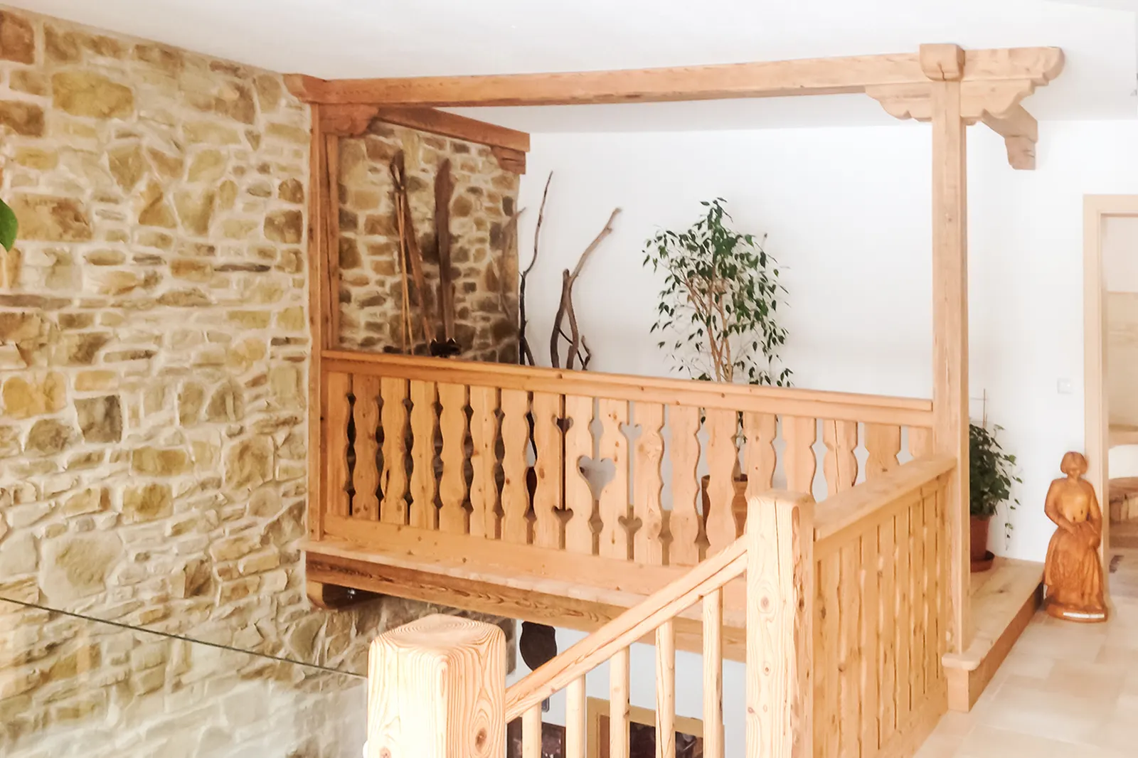Galerie mit Holzgeländer aus gedrechselten Stäben vor einer Natursteinwand